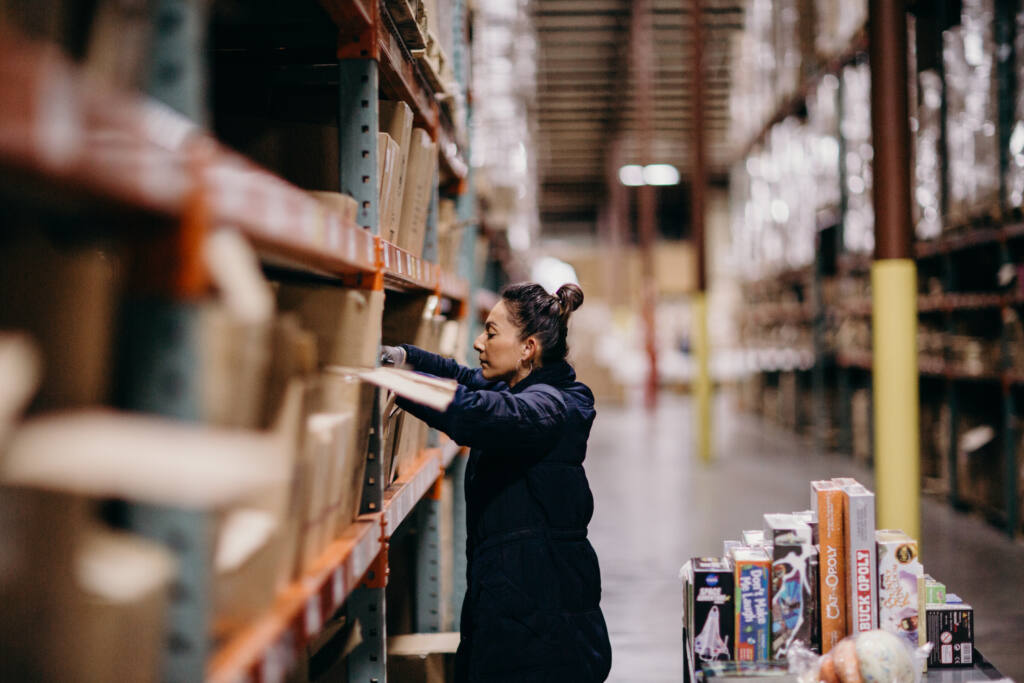 A Flat River Group warehouse employee retrieves pet supplies and pet-themed board games.